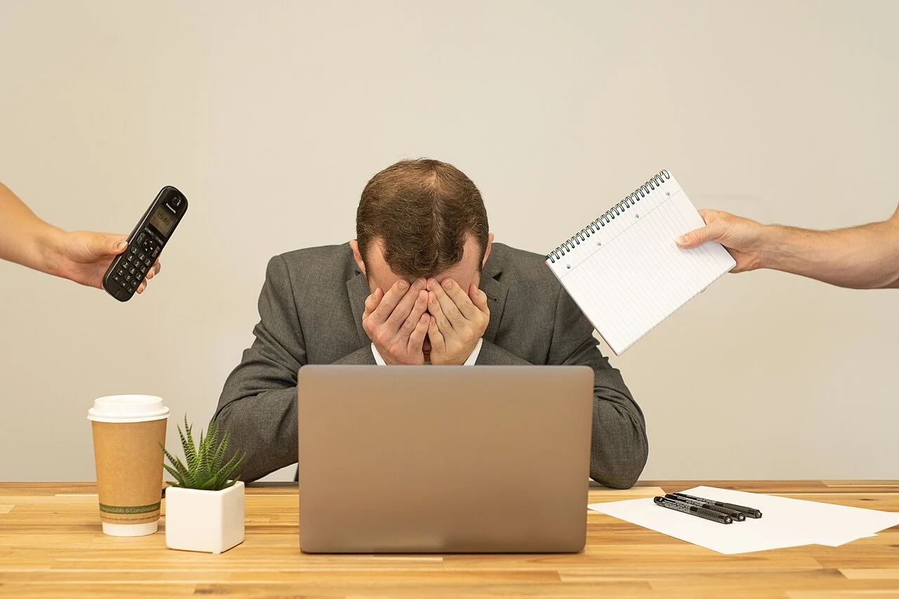 Profissional exausto em frente ao computador no escritório, ilustrando o esgotamento emocional da Síndrome de Burnout